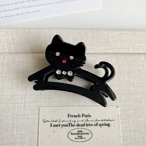 Détail d'une pince à cheveux chat noir ornée de strass brillants rouges et blancs