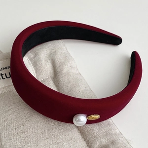 Detail of burgundy velvet headband with large white pearl and gold metal accent