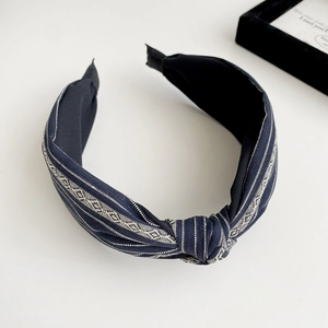Detail of navy fabric headband featuring exquisite cream geometric wave embroidery