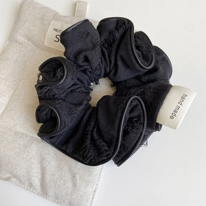 Detail of vintage black frayed edge scrunchie with handmade woven label on fabric