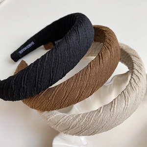 Three retro pleated sponge headbands in black brown and beige colors with a handmade label