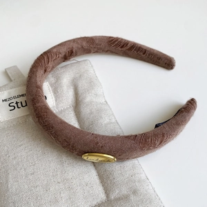 Close-up of vintage brown fabric headband with distressed texture and handmade gold metal plate
