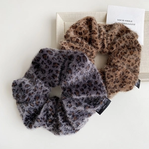 Detailed macro of leopard print faux fur scrunchies with soft fuzzy texture and woven label