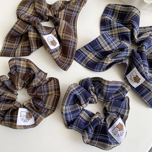 Detail of plaid scrunchies featuring bear embroidery patches and soft linen texture