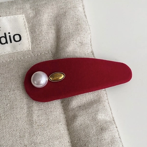 Macro shot of red velvet headband with white pearl and gold metal plate wings detail