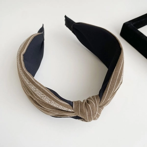 Close-up of retro brown striped headband with woven geometric texture and top knot detail
