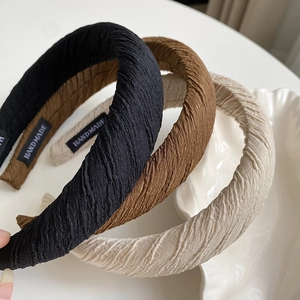 Detail showing stacked pleated sponge headbands in black, brown, and beige colors
