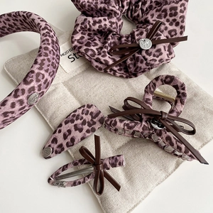 Detail of pink leopard print hair accessories set including headband and bow hair clips
