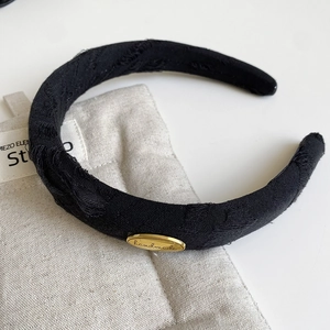 Detail of black fabric headband with vintage texture and gold handmade metal plaque