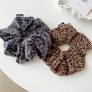 Plush leopard print scrunchies in grey and brown faux fur with decorative labels