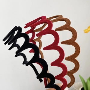 Détail de trois serre-têtes ondulés floqués en noir, bordeaux et marron avec velours