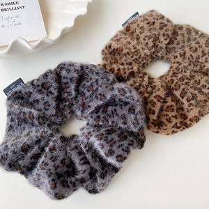 Detailed close-up of brown and grey leopard print faux fur scrunchies with woven labels