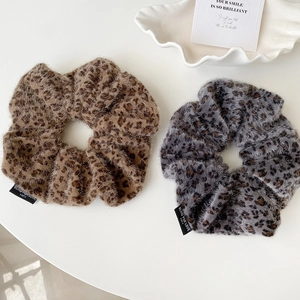 Detailed macro view of soft leopard print faux fur scrunchies with woven labels