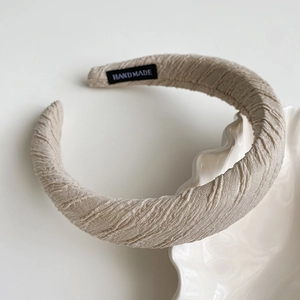Detail of beige pleated sponge headband with high-quality handmade woven label