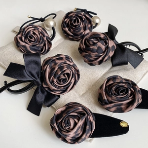 Detail view of leopard print rose hair accessories with pearls on a linen bag