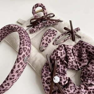 Detail of purple leopard hair accessory set with fabric textures and bow accents