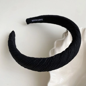 Detailed close-up of a pleated black sponge headband with a premium handmade textile label
