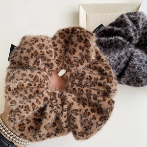 Close-up of fluffy leopard print faux fur scrunchies with soft plush texture and woven labels