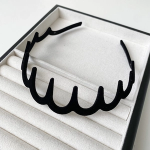 Détail d'un serre-tête ondulé floqué noir avec texture antidérapante dans son écrin