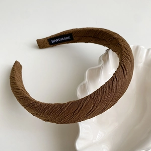 Detailed macro view of the handmade label and pleated brown fabric texture on the headband