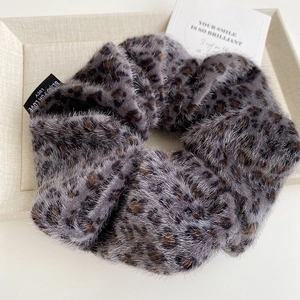Close-up of plush leopard print scrunchie with Blind for Love label in cream tray