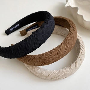 Detail of handmade pleated sponge headbands in black, brown, and cream white fabric textures