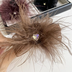 Detail of coffee feather hair claw clip with a sparkling heart crystal and organza base