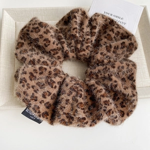 Detail of leopard print fuzzy scrunchie with Blind For Love woven label on plush fabric