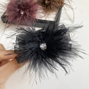 Detail view of a black feather hair claw clip with crystal heart and mesh bow