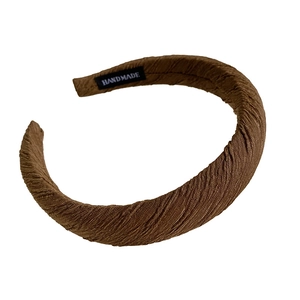 Brown pleated sponge headband with handmade label on a clean white background