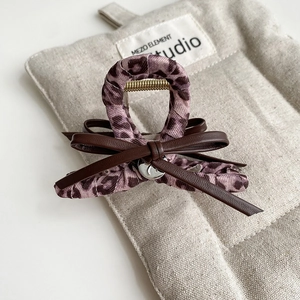 Close-up of pink leopard print hair claw with leather bow and strong metal spring