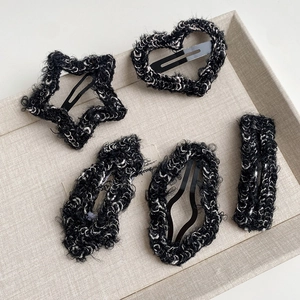 Detailed close-up of 5 plush tweed hair clips in star and heart shapes on a tray
