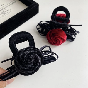 Close-up of velvet rose hair claw clips in black and red with elegant ribbon details