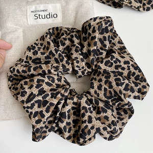Detailed close-up of a vintage brown leopard print scrunchie with soft pleated fabric texture