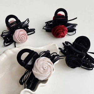 Detail of elegant velvet rose hair claws with ribbon tassels in four colors on a white plate