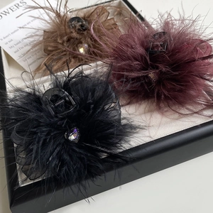 Macro detail of three elegant feather hair claws with rhinestones on a beige tray