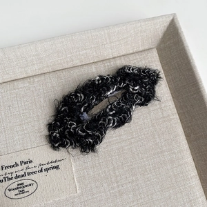 Detail view of plush black and white textured fabric hair clips on a beige tray