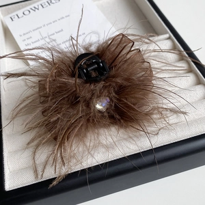 Brown feather hair claw with rhinestone heart and mesh bow on white velvet tray