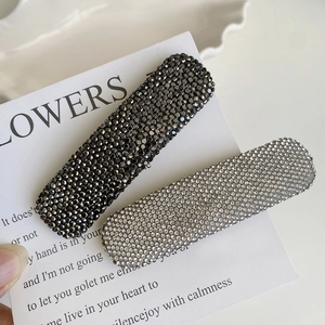 Close-up of sparkling rhinestone hair clips in dark grey and silver white on a white card