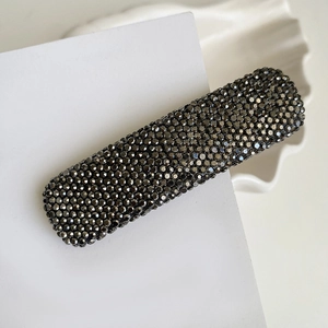 Detailed macro view of gunmetal grey hair clip with full rhinestone inlay on white card