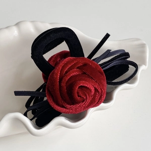 Detailed view of an elegant burgundy rose hair claw with velvet trim on shell tray