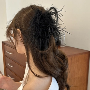 Detail of elegant black feather hair claw clip for a voluminous updo hairstyle