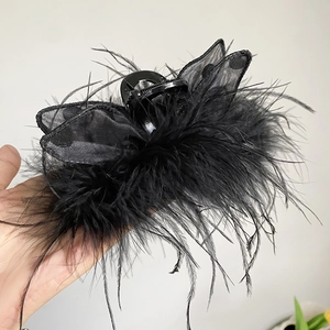 Detailed close-up of a black feather hair claw clip with mesh polka dot bow detail