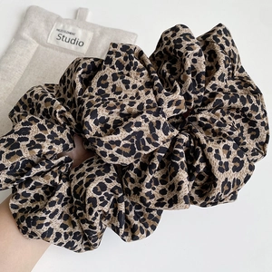 Vintage leopard print scrunchie in brown fabric held by hand for autumn style