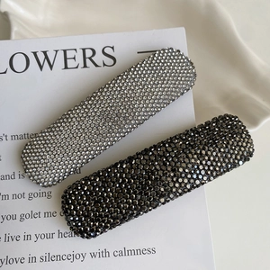 Close-up of sparkling rhinestone hair clips in silver and black on a white card