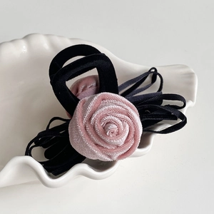 Detail of pink satin rose hair claw with velvet ribbon on a white shell tray