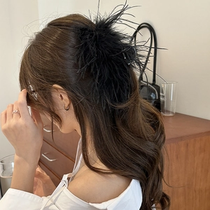 Detailed view of plush black feathers on a large hair claw clip worn on hair