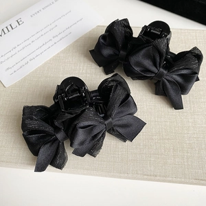 Détail de la pince à cheveux noire avec nœud en satin et résille aux bords brillants