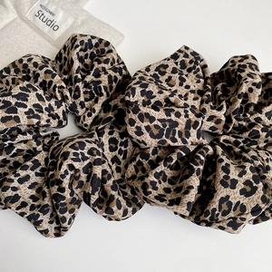 Close-up of leopard print scrunchies in brown fabric with pleated texture and stylish patterns