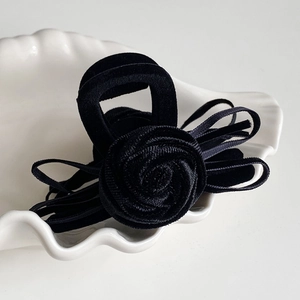 Detail of elegant black velvet hair claw clip with a 3D rose flower and bow ribbons